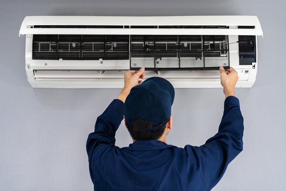 Technicien retirant le filtre d'une unité murale pour la nettoyer