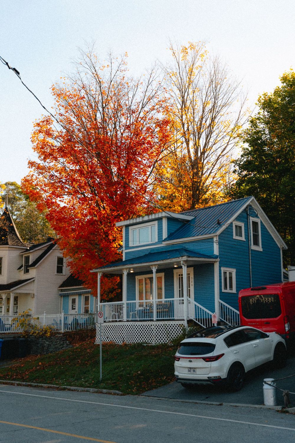 Maison bleue à galerie entourée d'érables en automne, au Québec
